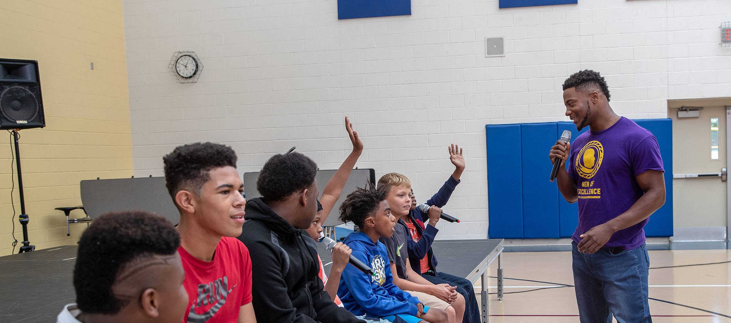 Man talking with a group of boys in a gym
