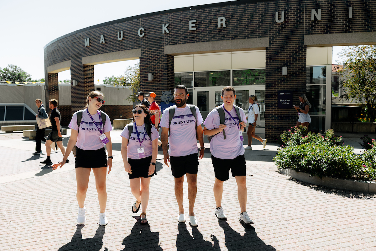 Student affairs alum walking with orientation staff at UNI