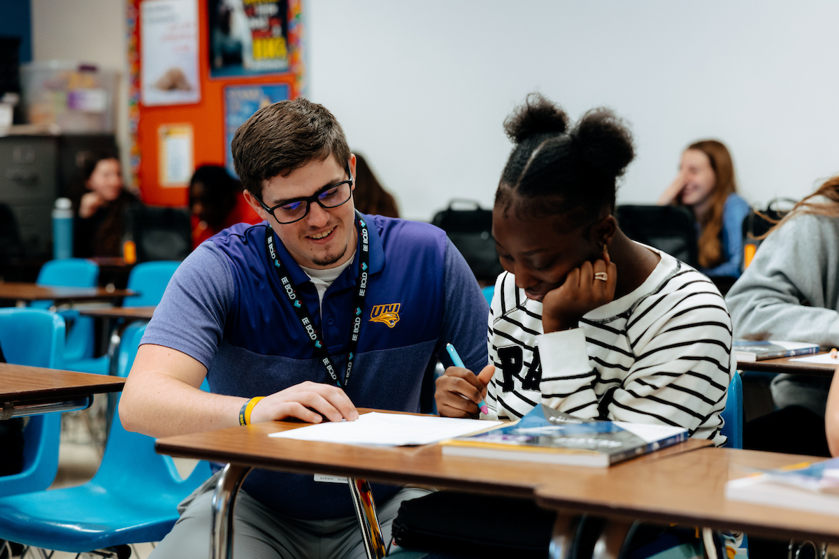 Middle school student teacher working with math students