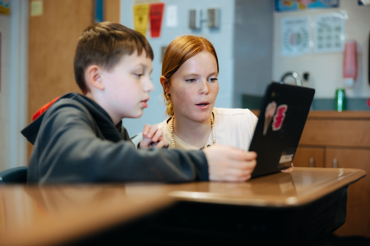 Student teacher working with student in classroom