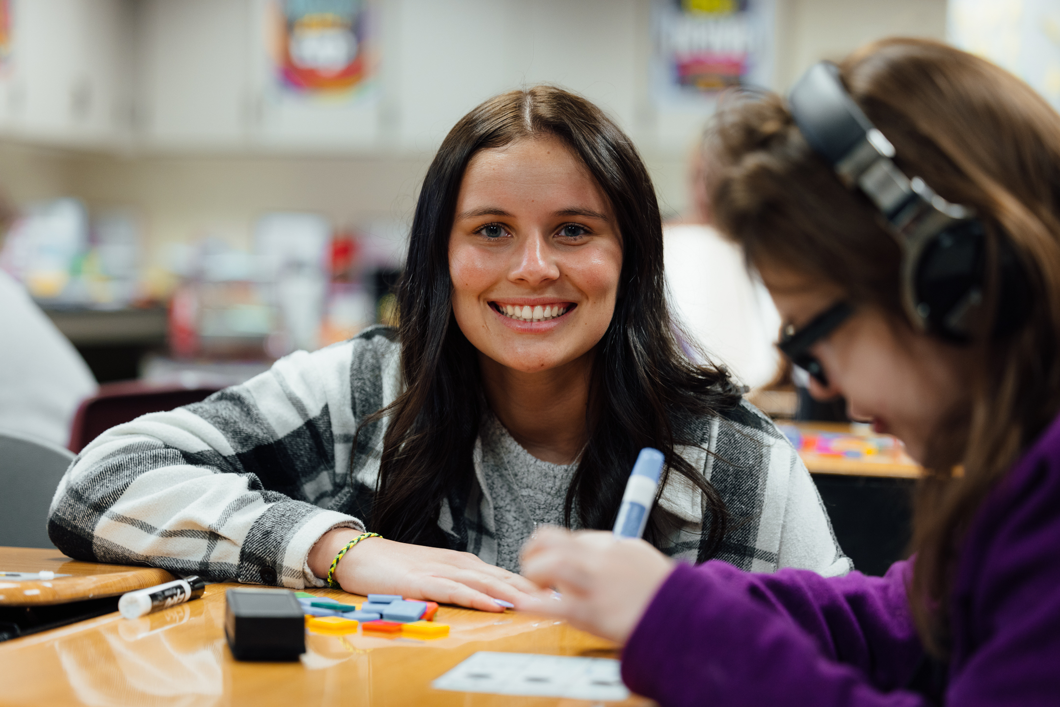 student teacher at desk with  student with headphones on 