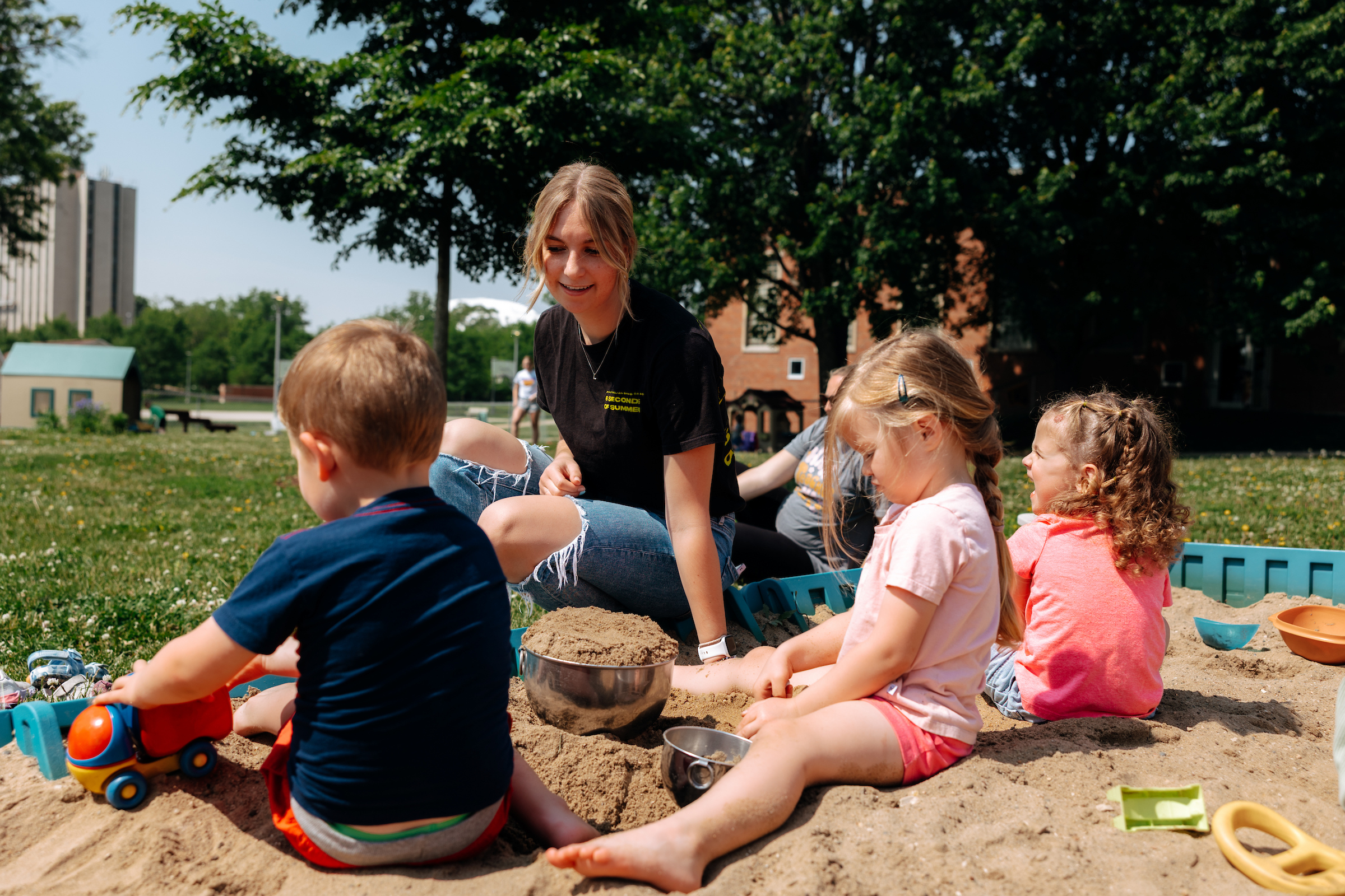 Student teacher with four and five-year-olds in sandbox 