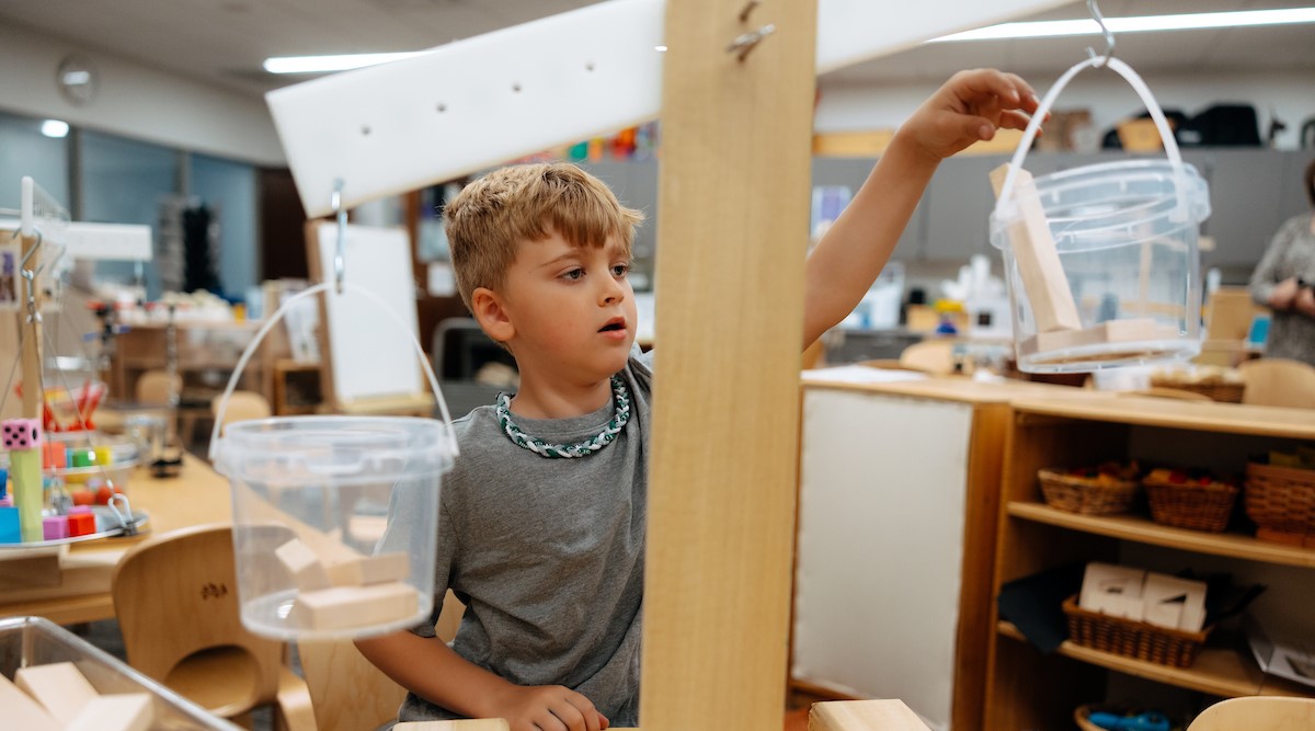 Student working on balance with blocks and weights in early childhood model classroom