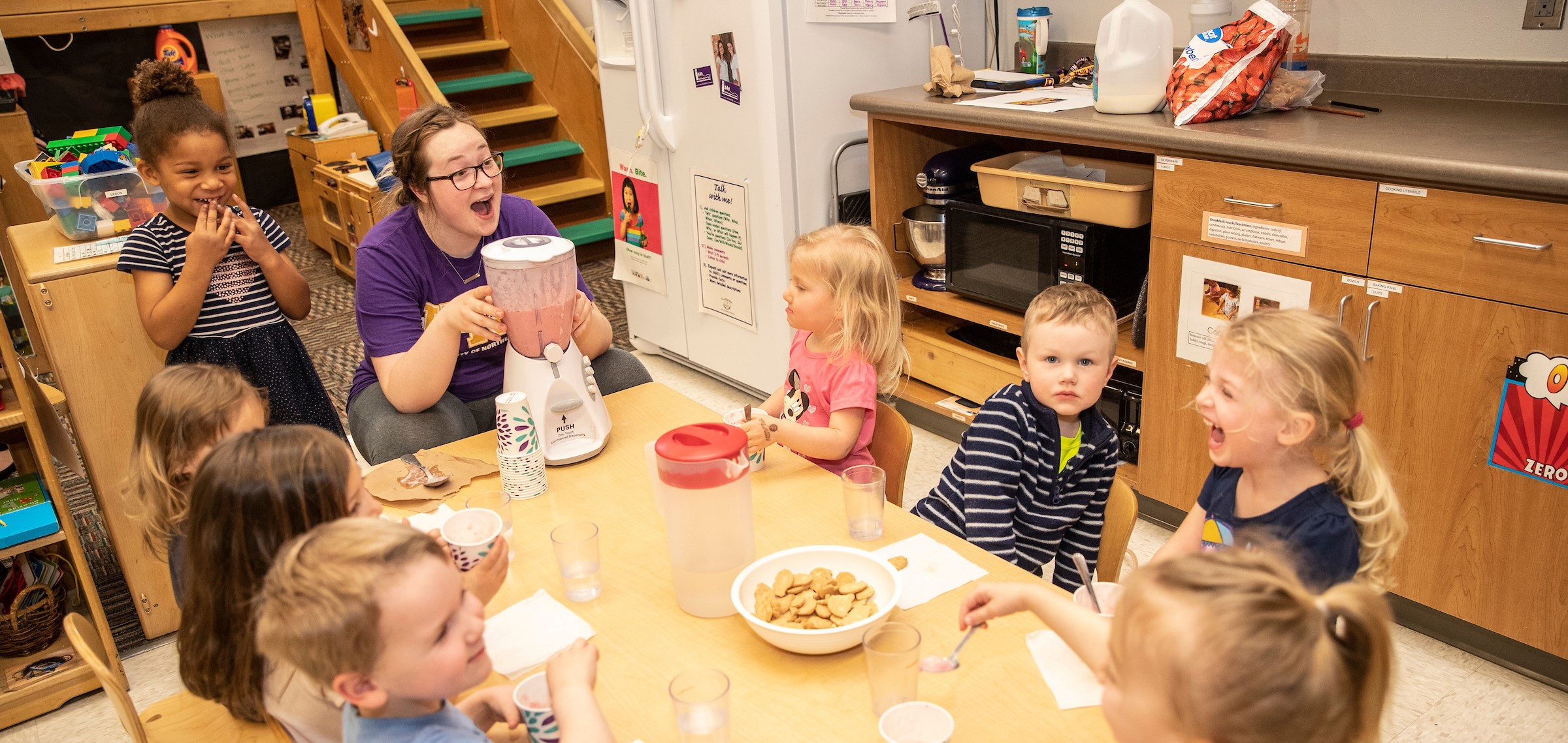 kids and teacher gathered around table at child development center