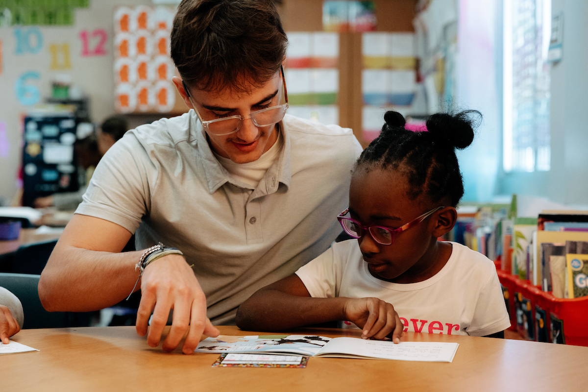 Student teacher working with elementary student at table