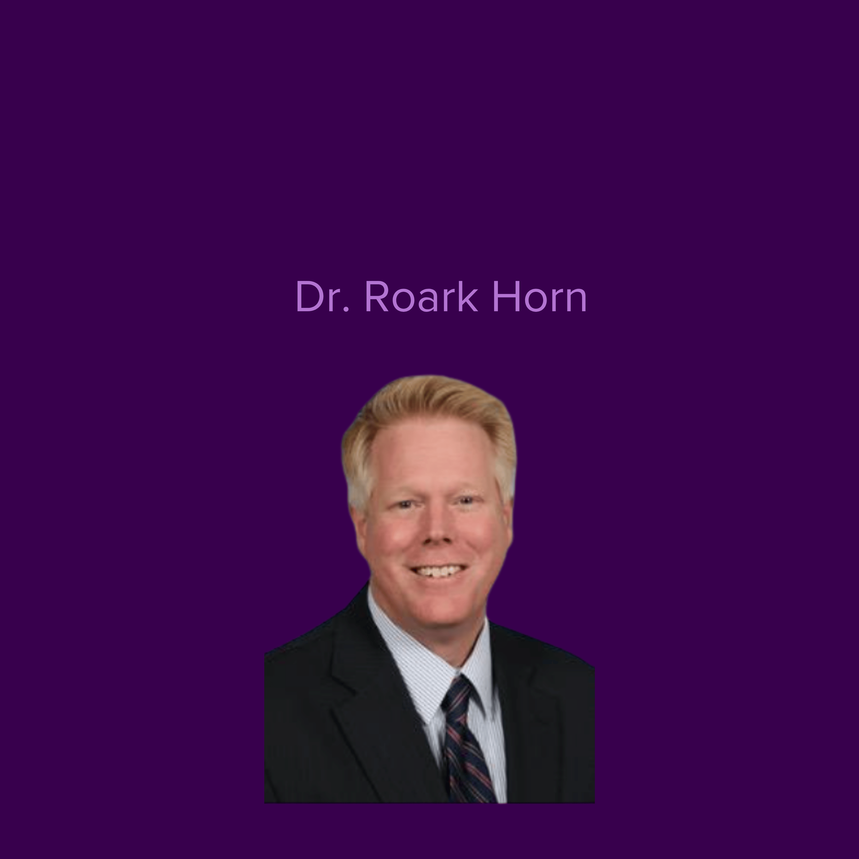 Image of Dr Roark Horn wearing a dark suit jacket and tie