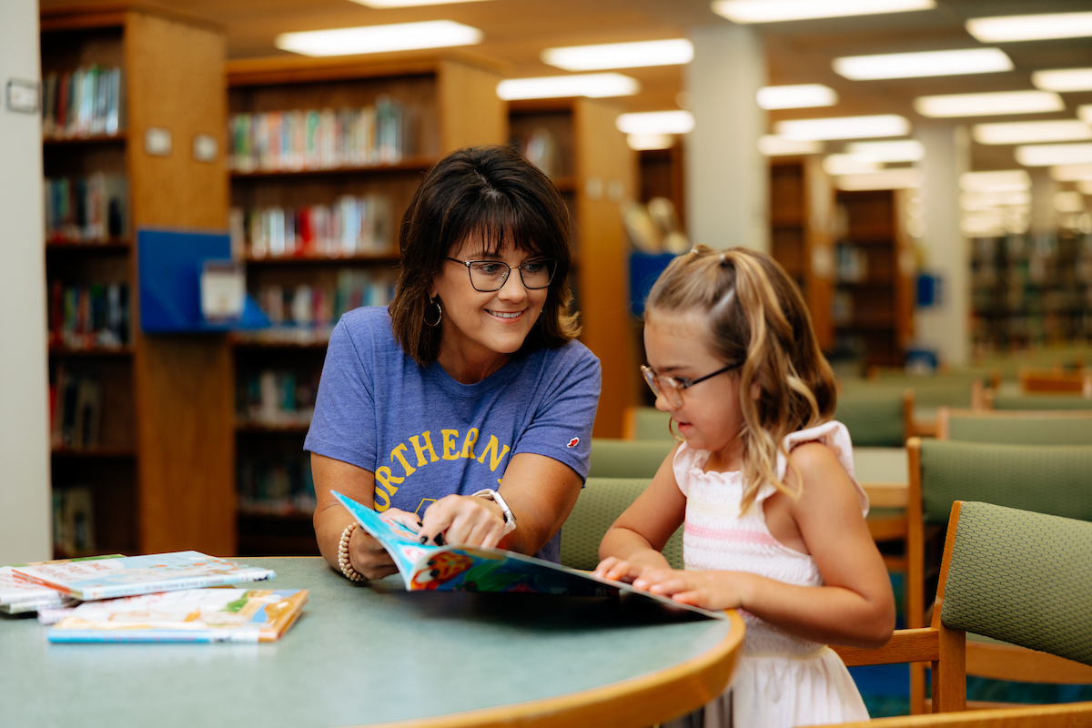 Teacher librarian student in library with child 